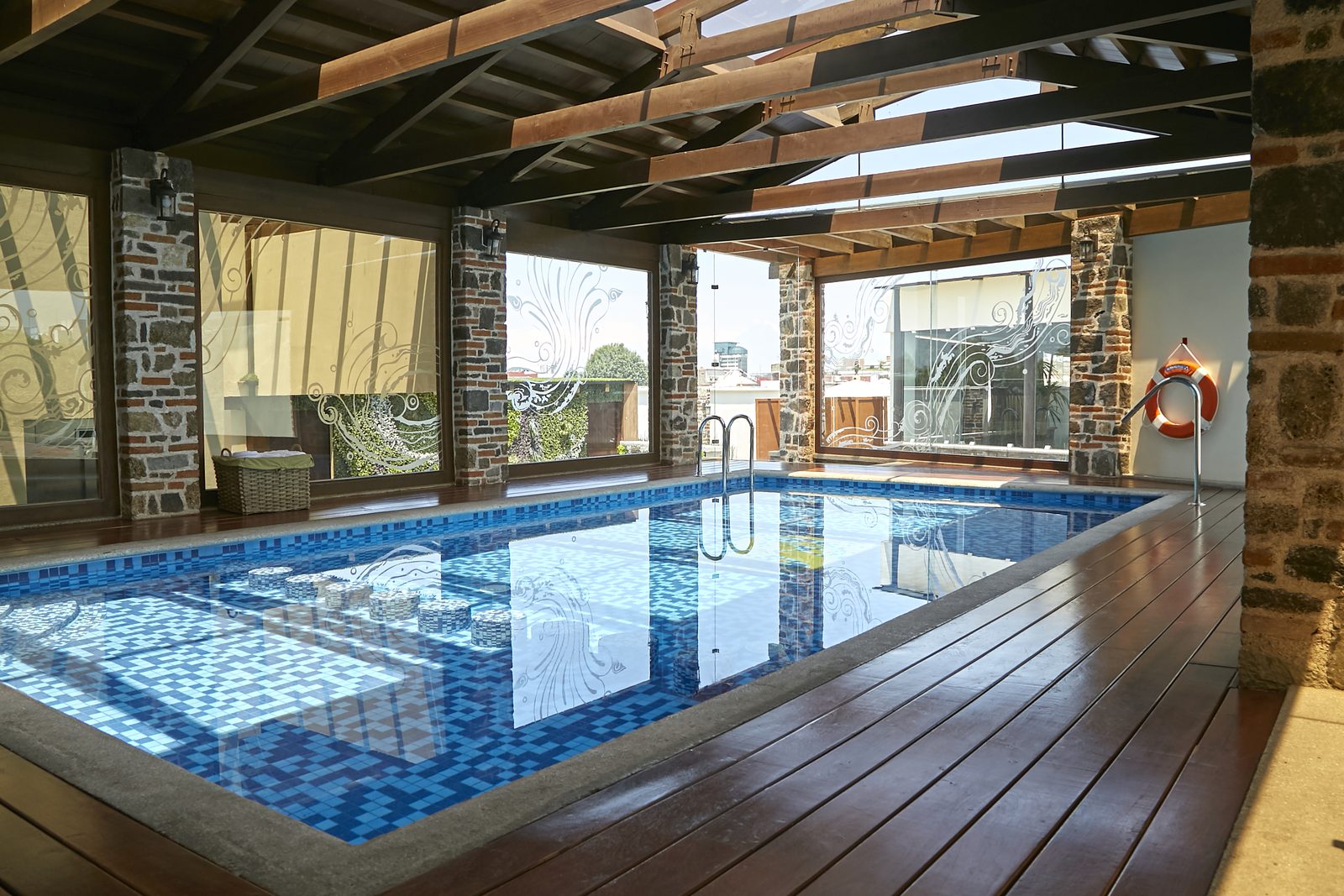 Alberca techada de la Casona de los Sapos con cubierta de madera y vidrio y muros de piedra.