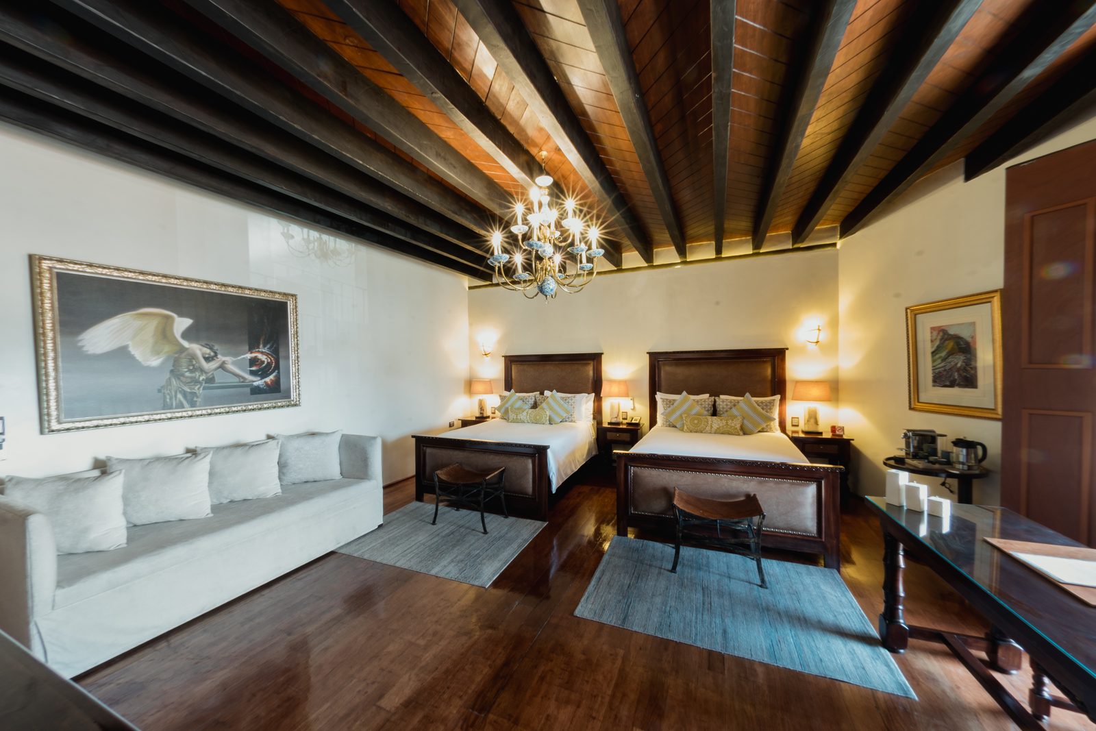 Suite Doble de Lujo con dos camas y sofá cama, techo de vigas y candelabro.